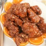 Air Fryer Orange Chicken on a plate with white rice and orange slices.