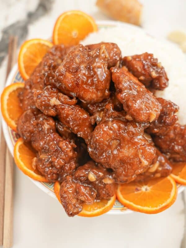 Air Fryer Orange Chicken on a plate with white rice and orange slices.