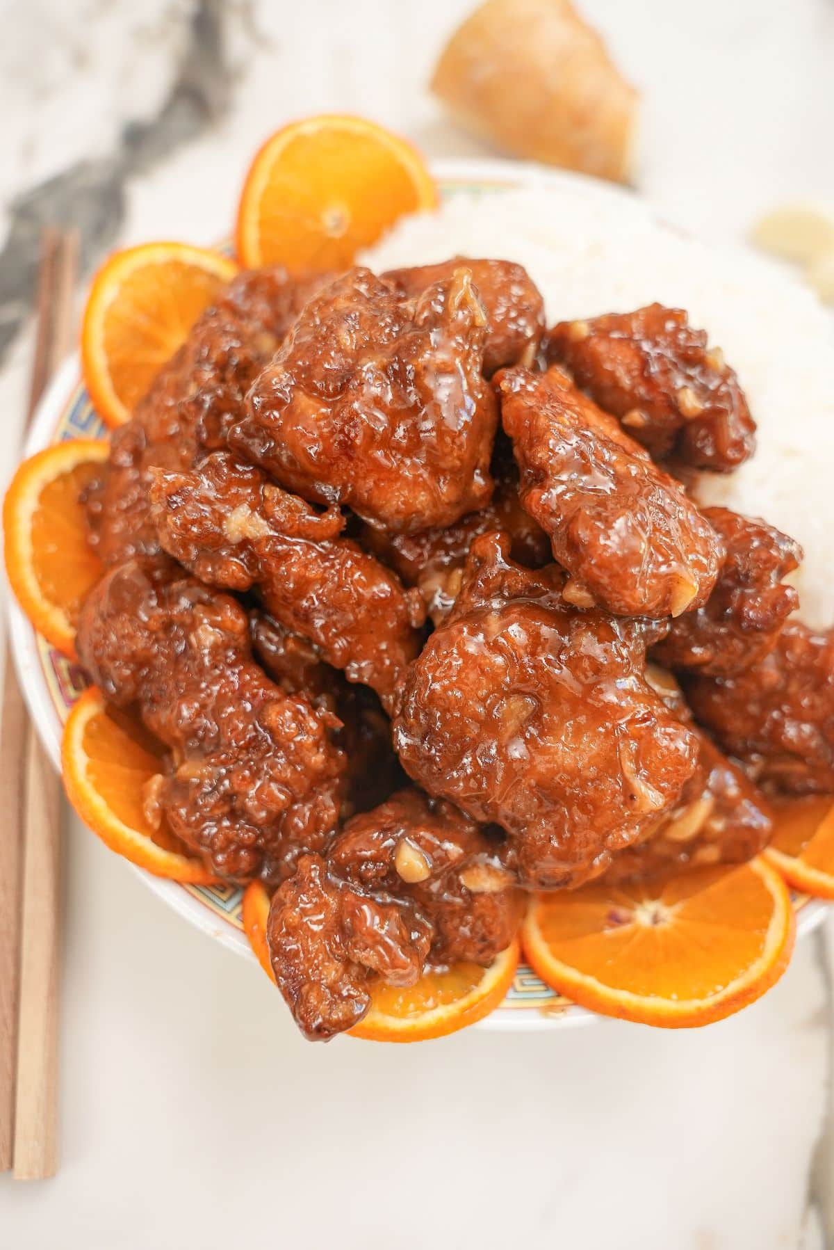Air Fryer Orange Chicken on a plate with white rice and orange slices.