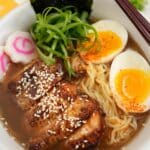 Chicken Ramen plated in a bowl with chicken, ramen noodles, soft boiled egg, scallions, and nori.