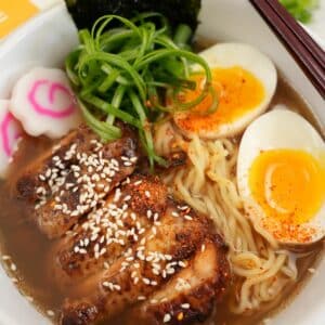 Chicken Ramen plated in a bowl with chicken, ramen noodles, soft boiled egg, scallions, and nori.