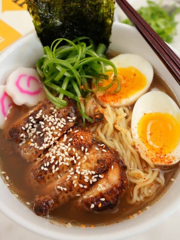Chicken Ramen plated in a bowl with chicken, ramen noodles, soft boiled egg, scallions, and nori.