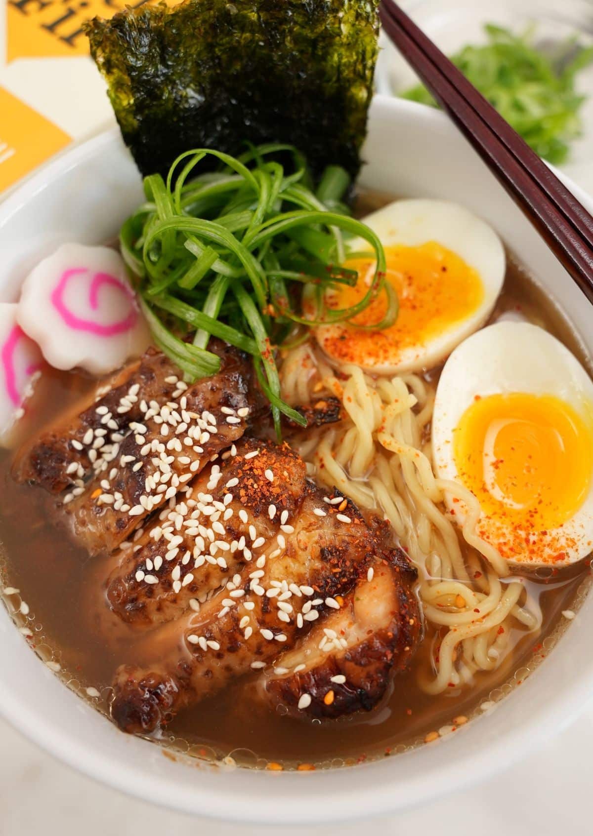 Chicken Ramen plated in a bowl with chicken, ramen noodles, soft boiled egg, scallions, and nori.