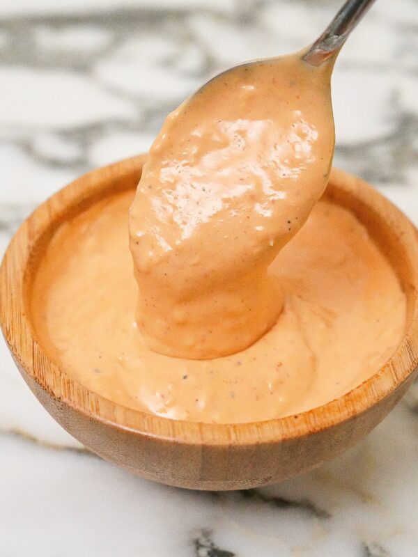 Spicy mayo sauce prepared in a wooden bowl with a spoon.