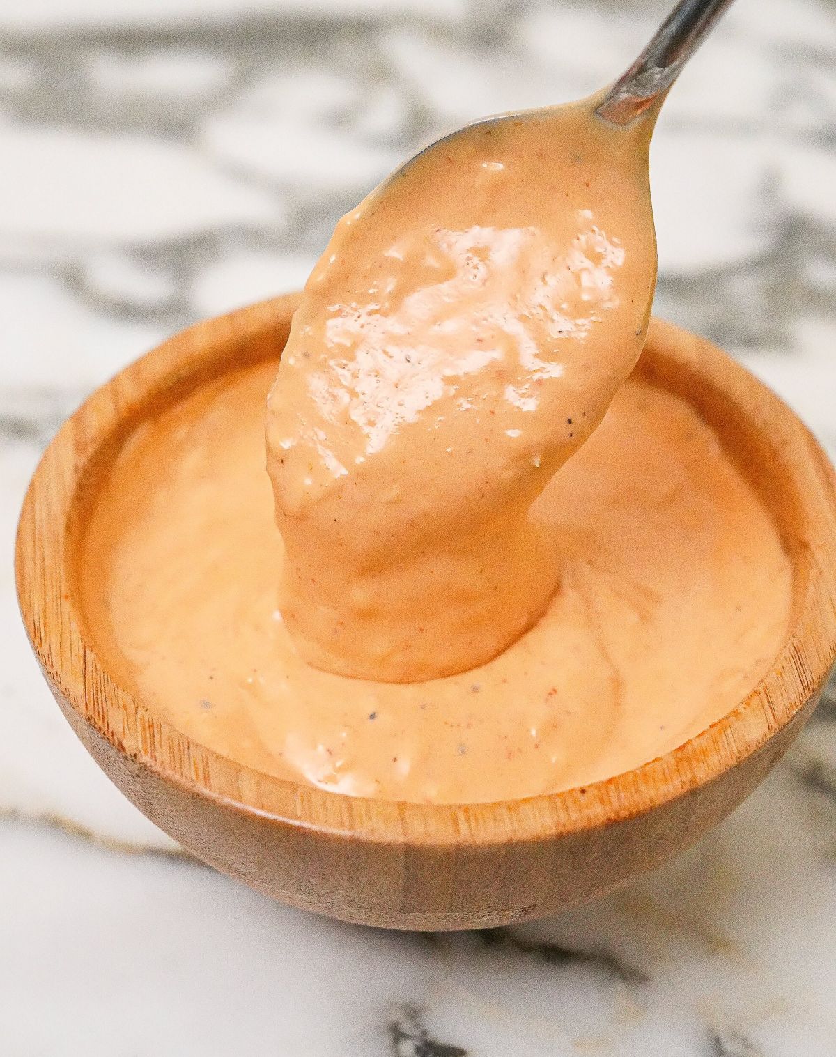Spicy mayo sauce prepared in a wooden bowl with a spoon.