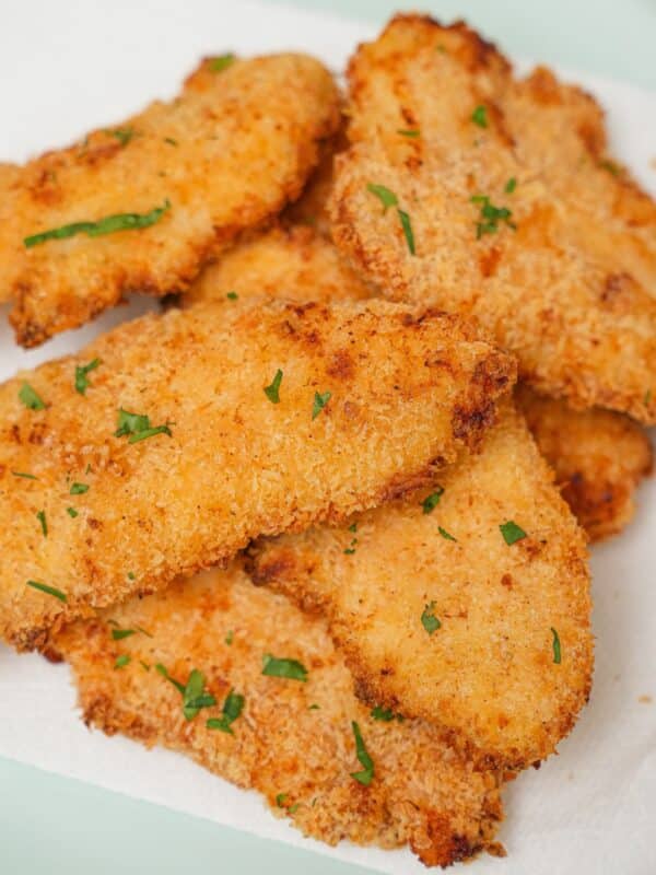 A plate of crispy and juicy air fryer chicken tenders stacked on top of each other.