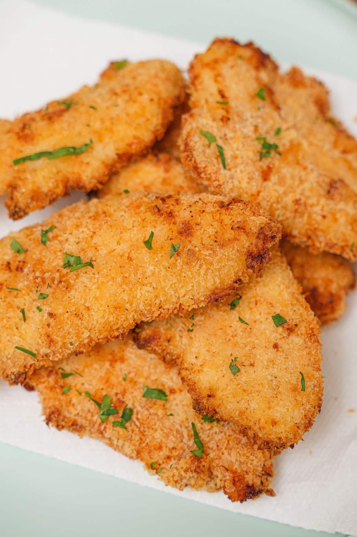 A plate of crispy and juicy air fryer chicken tenders stacked on top of each other.