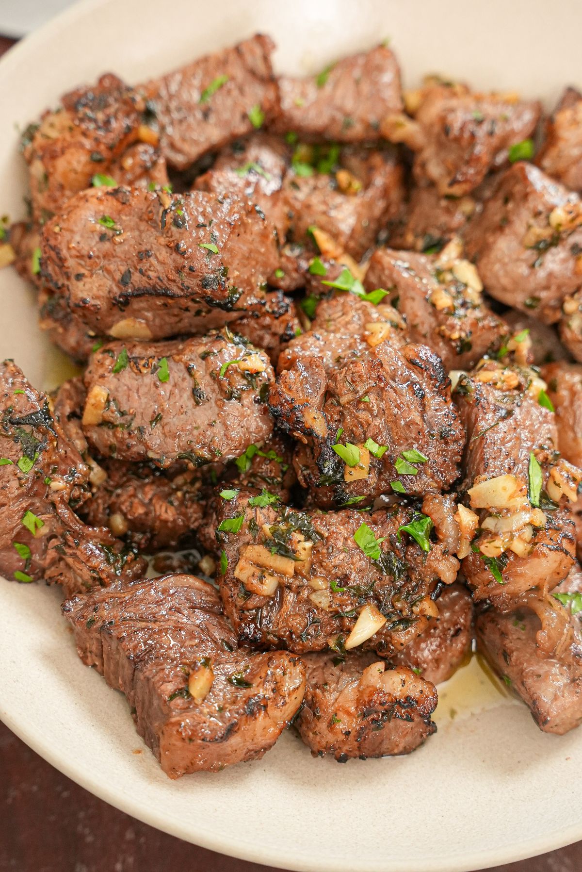 Cooked air fryer steak bites in a bowl tossed in an herb garlic butter.