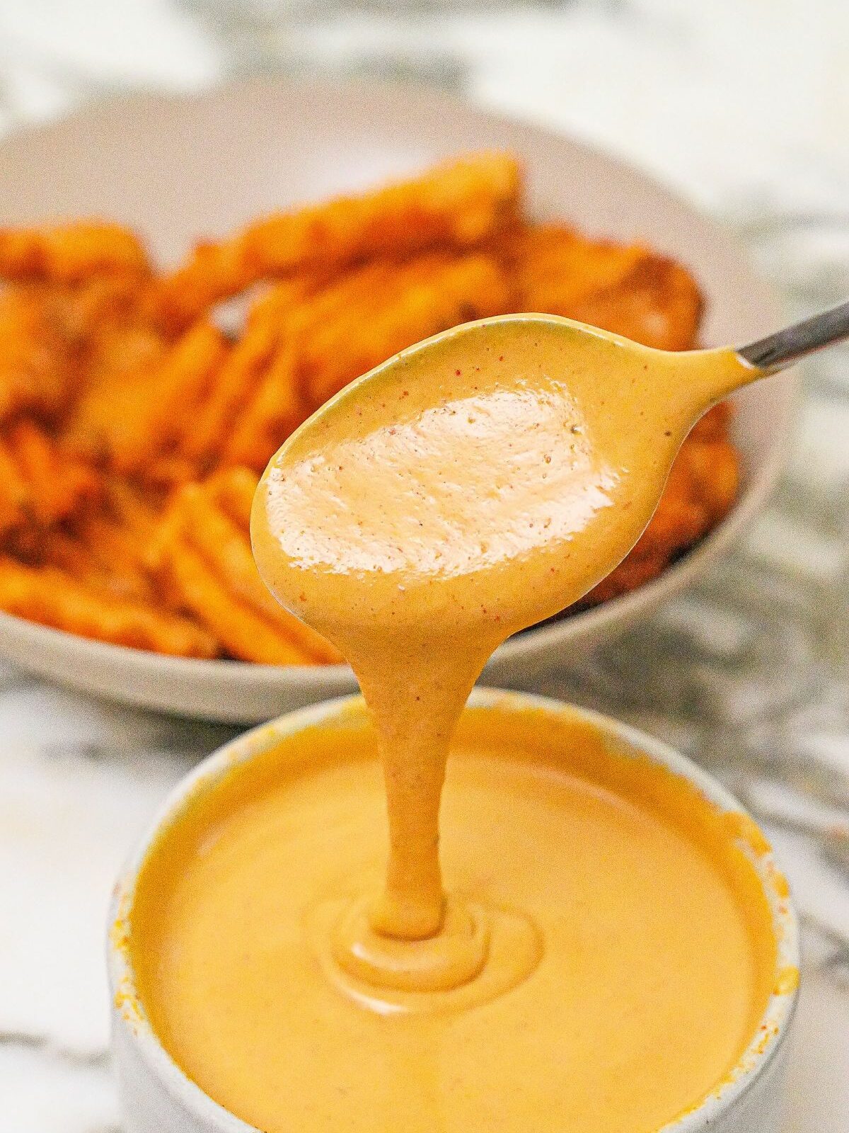 Copycat Chick-fil-a-sauce in a bowl next to a bowl of fries.