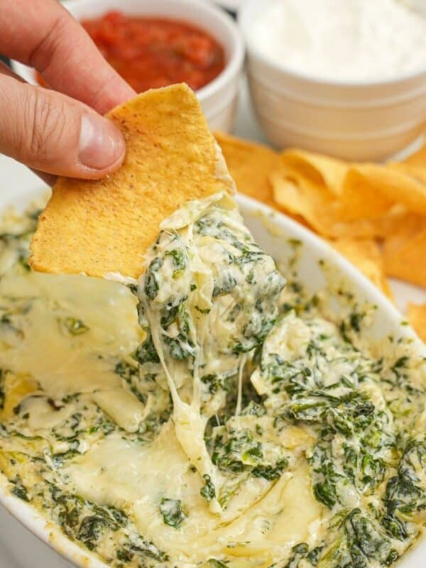 A chip scooping Houstons Copycat Spinach Artichoke dip with chips.