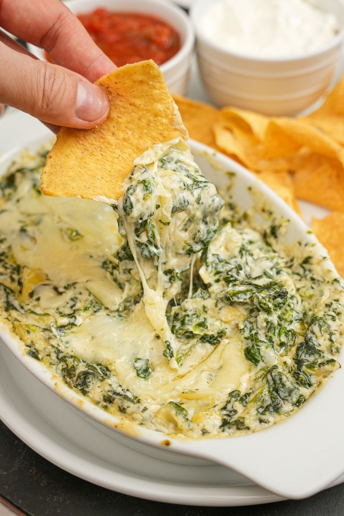A chip scooping Houstons Copycat Spinach Artichoke dip with chips.