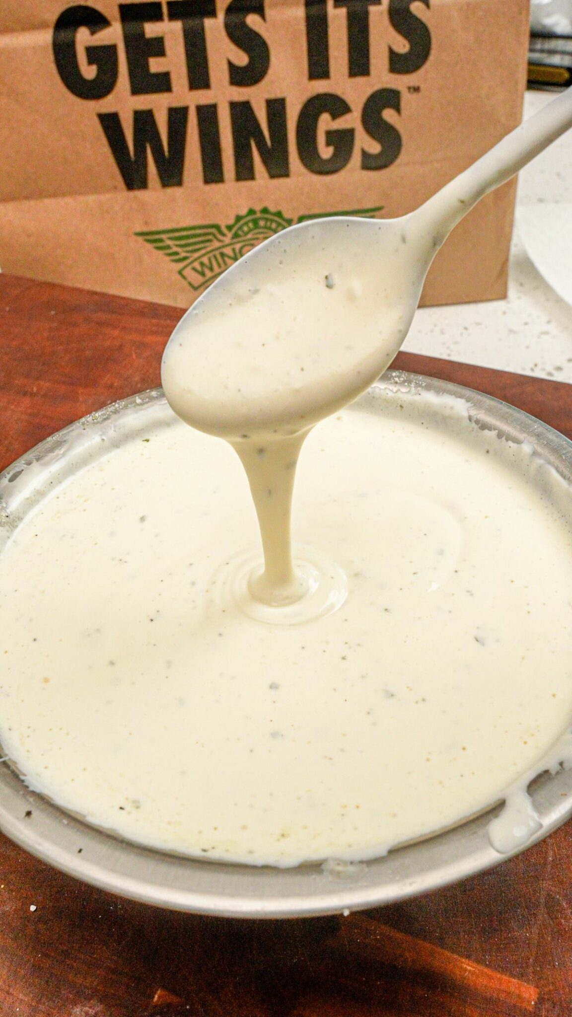 Copycat Wingstop ranch in a metal bowl in front of a wingstop paper bag.